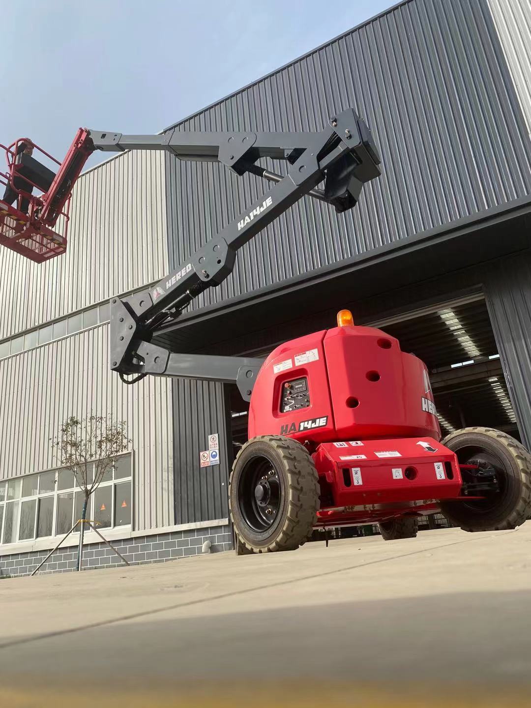 Red HERED HA14JE articulating boom lift in stowed position, rear three-quarter view