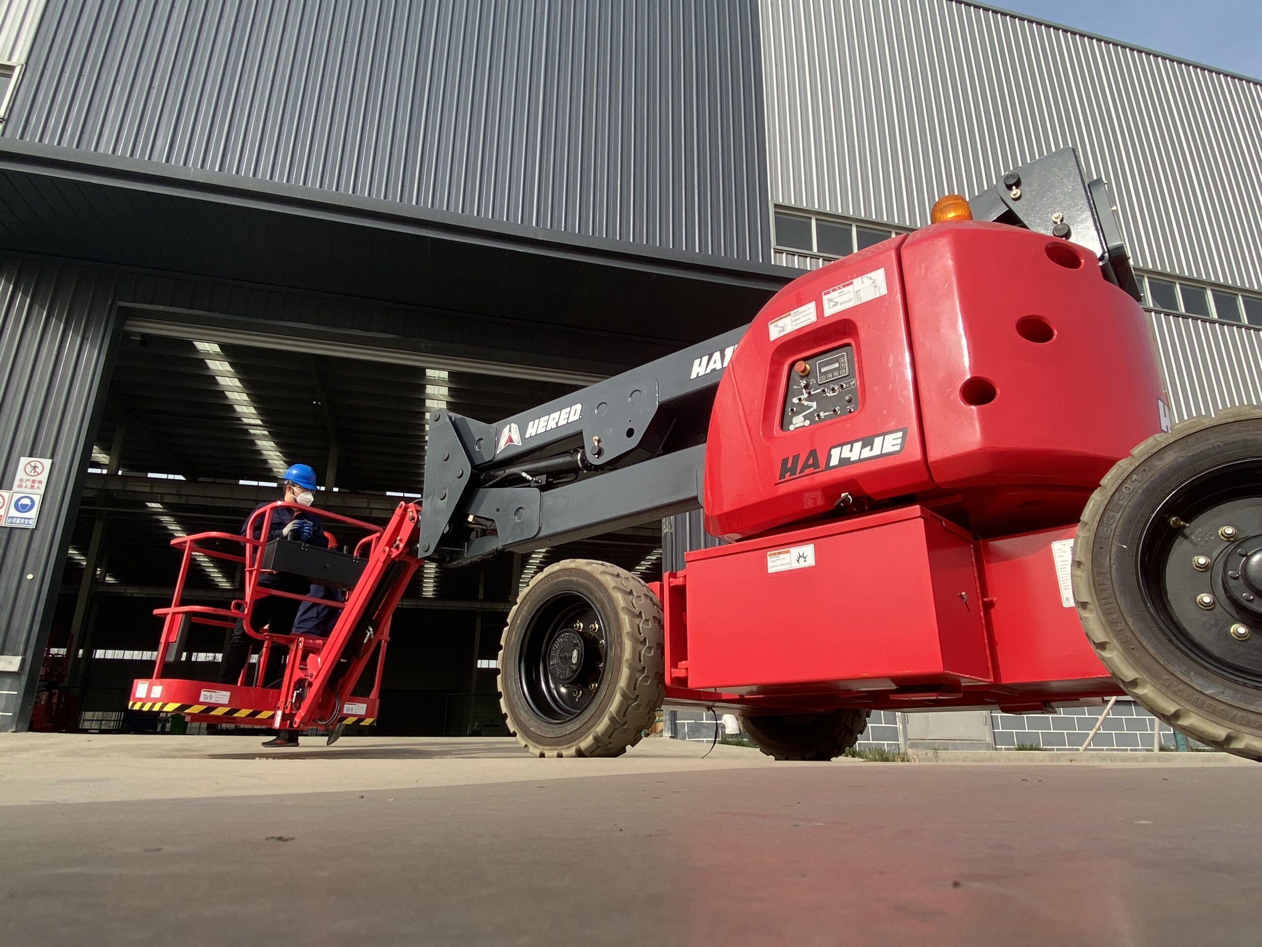 Red HERED HA14JE articulating boom lift in stowed position, rear three-quarter view