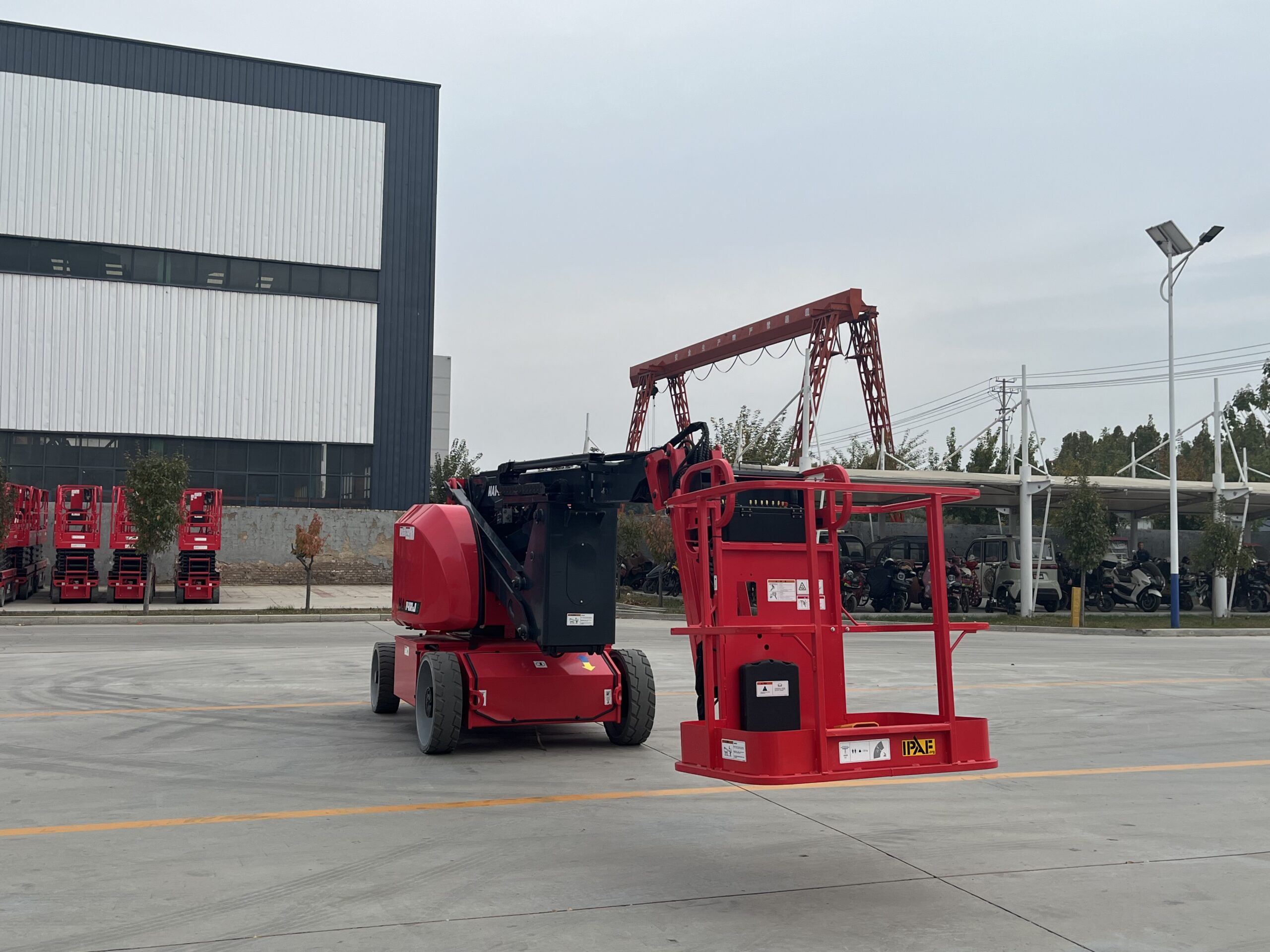Red HERED HA14RJE articulating boom lift in stowed position, rear view